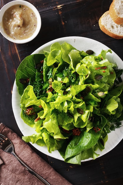 Plate fresh green salad flax seeds dark wooden  Diet food