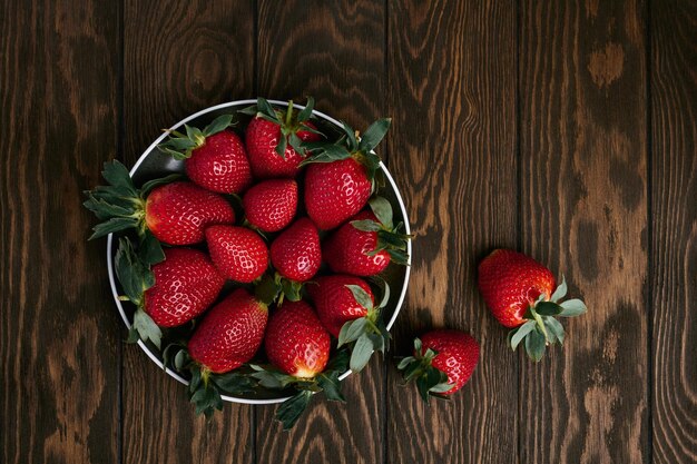 Plate of fresh strawberries on wooden table in closeup