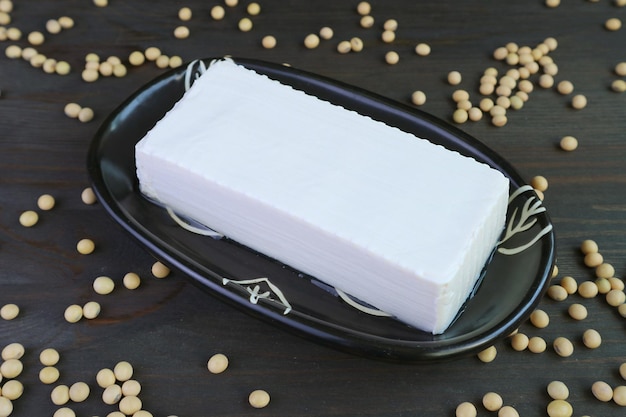 Plate of Fresh Tofu Bean Curd on with Dried Soybeans Scattered on Wooden Table