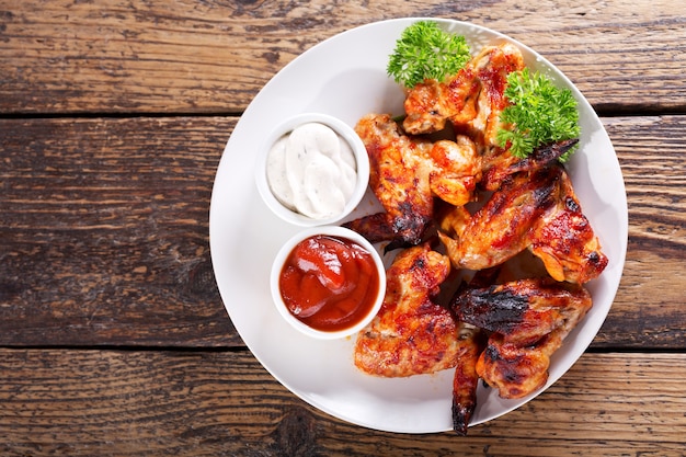 Plate of fried chicken wings on wooden table, top view