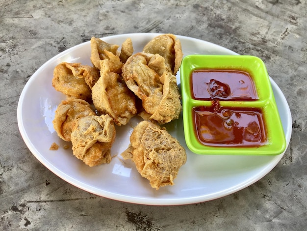 A plate of fried dumplings with sauces and a green plate with the word fried on it.