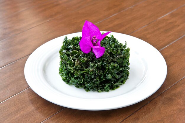 Plate of fried parsley garnished with bougainvillea flower on wooden table contemporary food