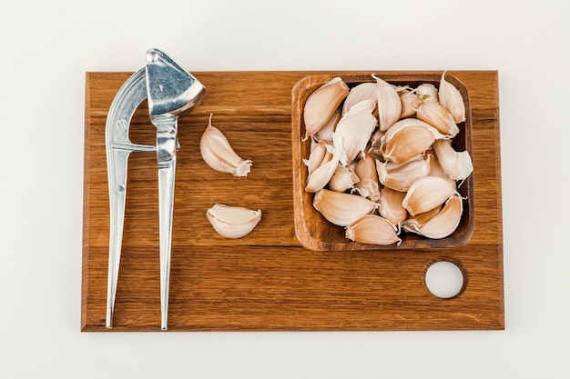 A plate of garlic with squeeze and cutting board isolated on white background