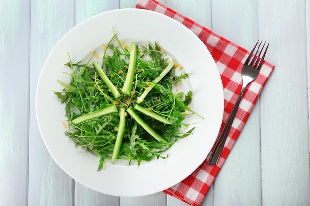 Plate of green salad with cucumber arugula and rosemary on wooden table top view