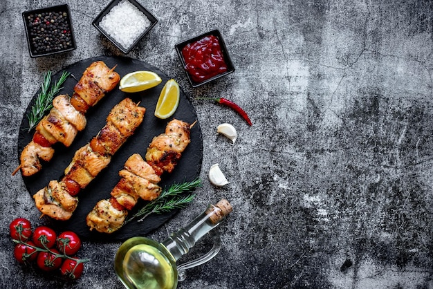 A plate of kebabs with lemon and garlic on a dark background