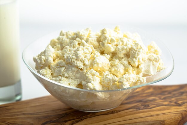 in a plate, large pieces of cottage cheese, a glass with milk, cutting board, isolated background