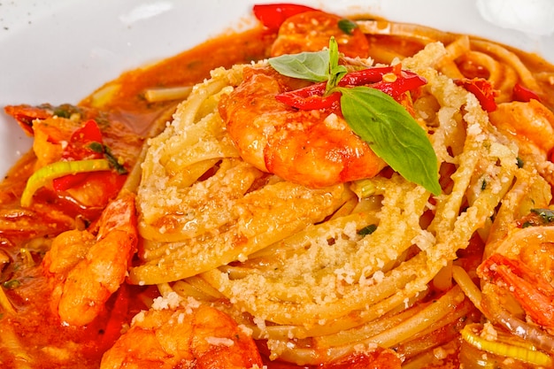 A plate of linguini with sauteed shrimp tomato chili and olive oil