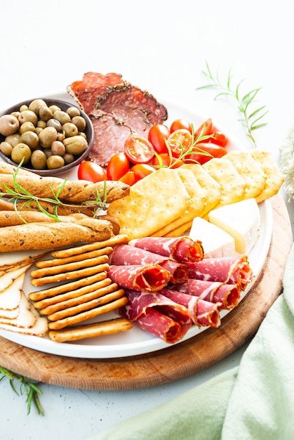 A plate of meats, cheese, and olives with a bowl of olives on the side.