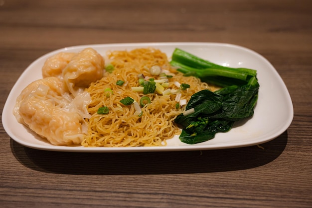 A plate of noodles with green vegetables and a plate of noodles.