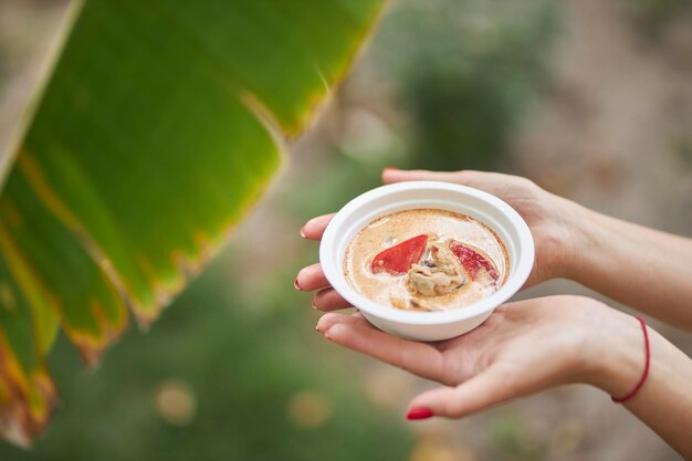 a plate of oriental spicy soup in female hands closeup