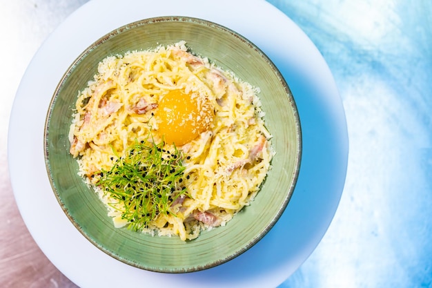 Plate of pasta carbonara cream sauce with bacon egg and micro green Italian spaghetti carbonara close up