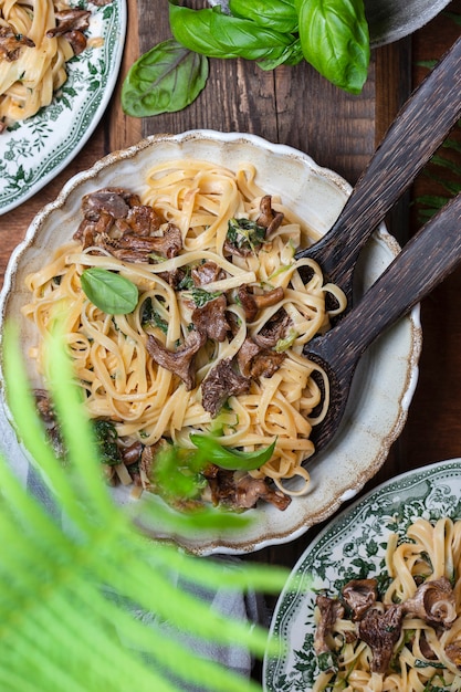 Plate of pasta with forest chanterelles and green basil