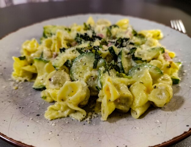 Photo a plate of pasta with zucchini and cheese on it