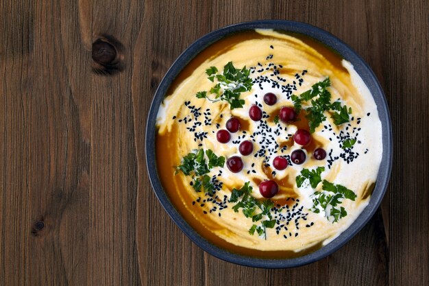 Plate of pumpkin cream soup black cumin seeds herbs and cranberries