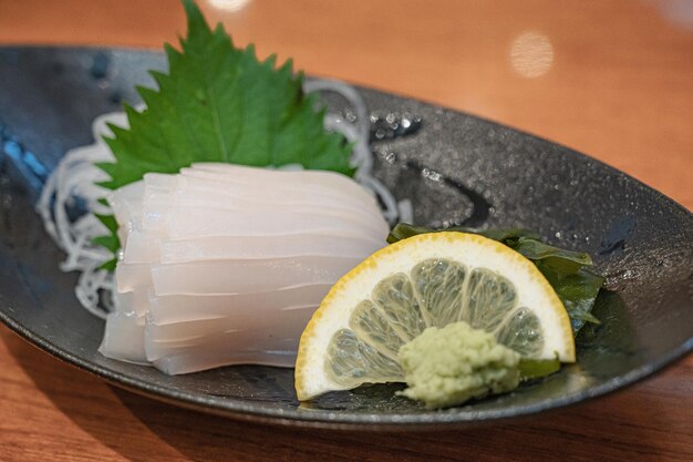 A plate of raw fish with a lemon slice on it