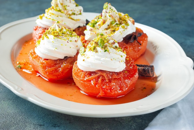 A plate of red tomatoes with whipped cream and pistachios