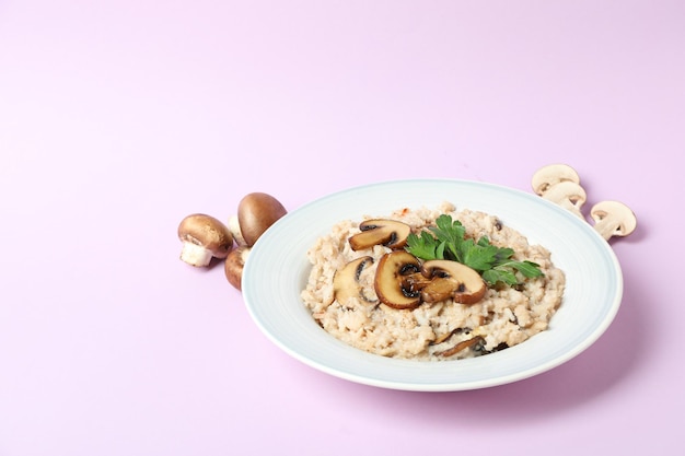 Plate of risotto with mushrooms and ingredients on violet background