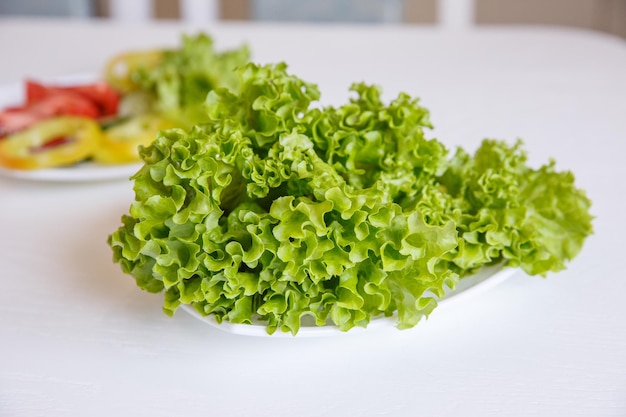 A plate of salad leaves is on the table in the kitchen