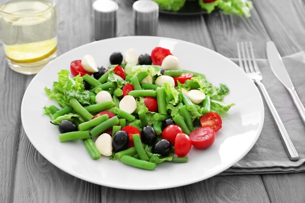 Plate of salad with green beans on wooden table