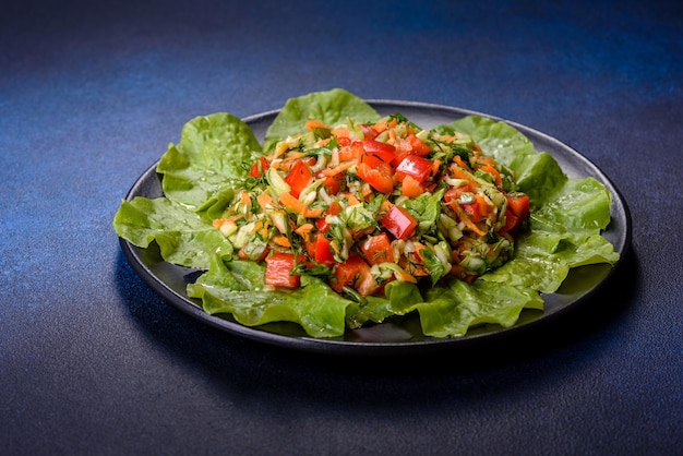 Plate of salad with vegetables and greens on a dark concrete table