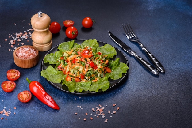 Plate of salad with vegetables and greens on a dark concrete table