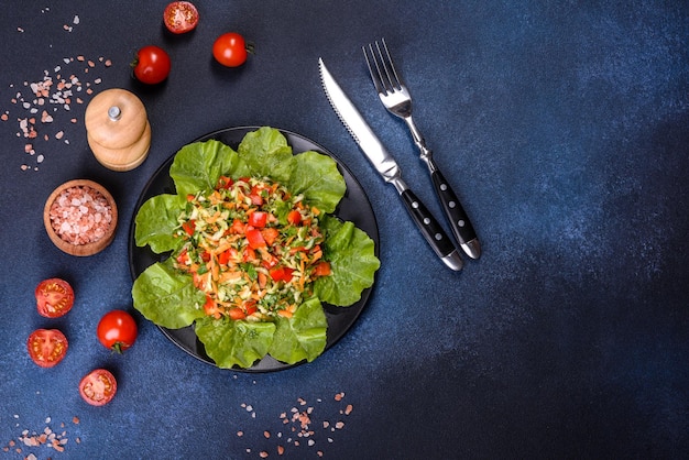 Plate of salad with vegetables and greens on a dark concrete table