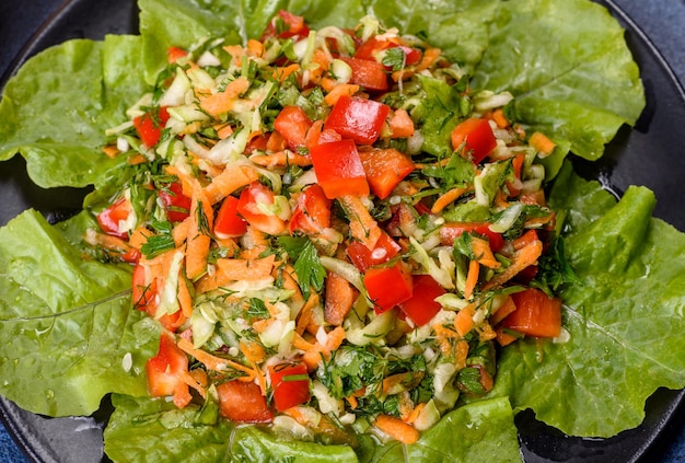 Plate of salad with vegetables and greens on a dark concrete table