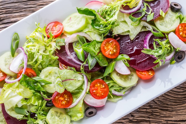 Photo plate of salad with vegetables  on rustic oak table assortment of ingredients of vegetable salad