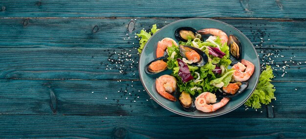 Photo a plate of seafood mussels squid shrimp top view on a blue wooden background copy space