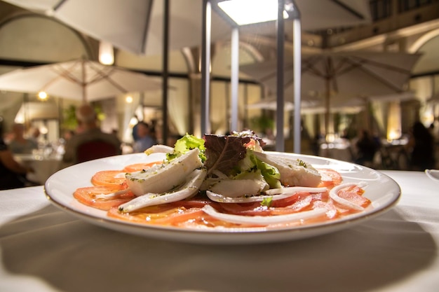 A plate of sliced tomatoes, topped with lettuce, onions and assorted cheeses. Haute cuisine concept.