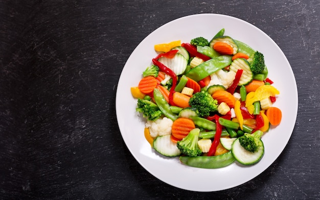 Plate of stir fry vegetables on a dark, top view