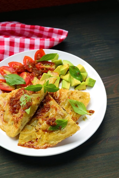 Plate of Tortilla de Patatas or Spanish Omelet with Avocado and Tomato Salad