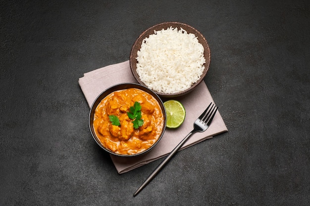 Plate of traditional chicken curry and rice on dark table