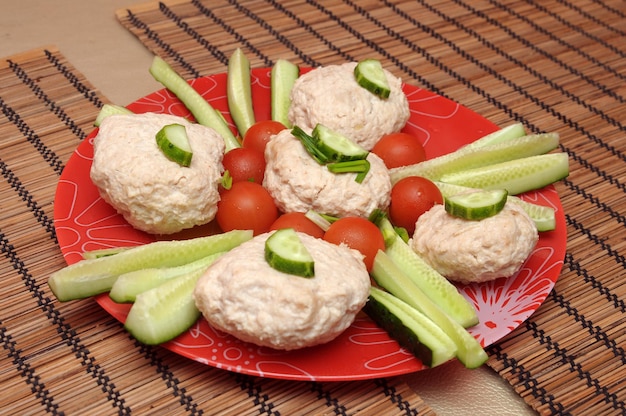 A plate of tuna salad with cucumbers and tomatoes on it