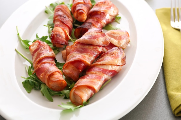 Plate with bacon wrapped chicken nuggets on table closeup