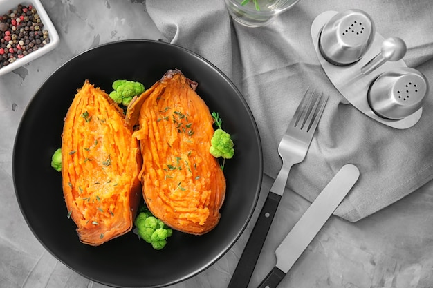 Plate with baked sweet potato on table