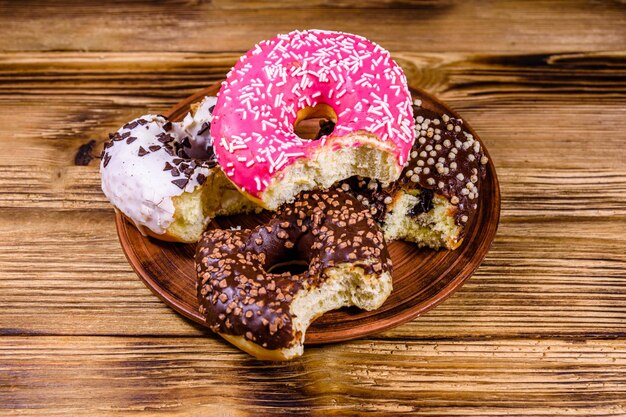 Plate with bitten glazed donuts on a wooden table