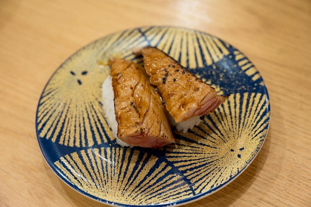 A plate with a blue and yellow plate that says " sushi " on it.