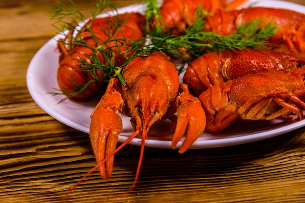 Plate with boiled crayfishes on wooden table