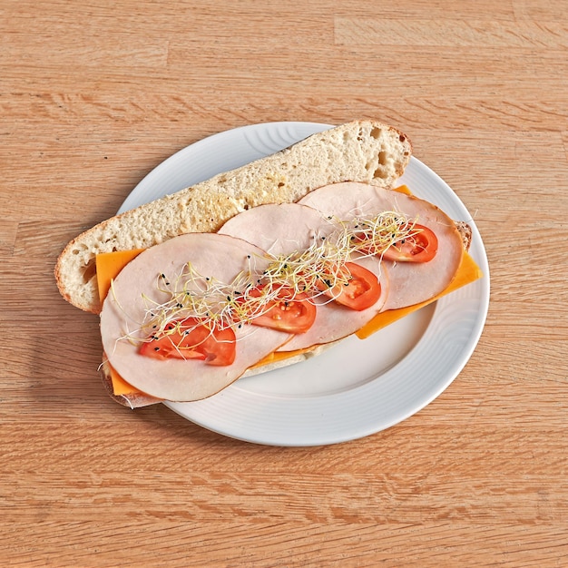 Plate with a Chicken and Cheddar sandwich on wooden table