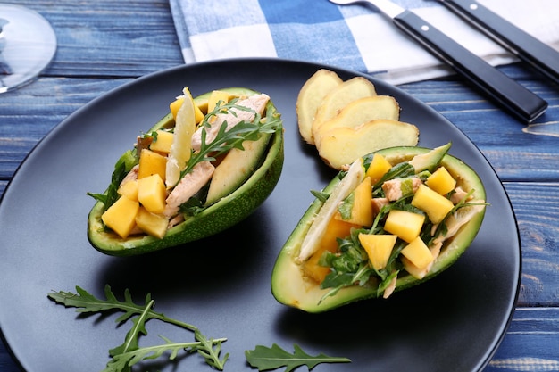 Plate with chicken salad in boats from avocado on table