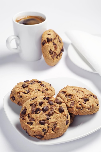 Plate with chocolate cookies and coffee cup on white background