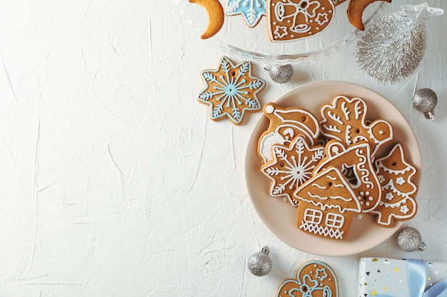 Plate with Christmas cookies, Christmas trees, toys, gift boxes on white, top view. Space for text