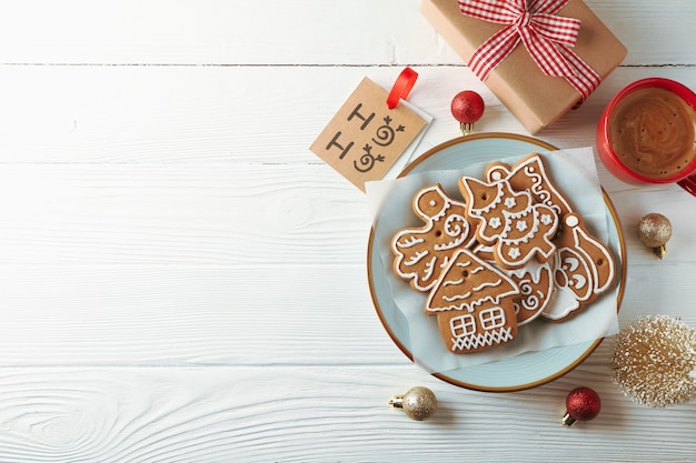 Plate with Christmas cookies, toys and coffee on white wooden, space for text. Top view