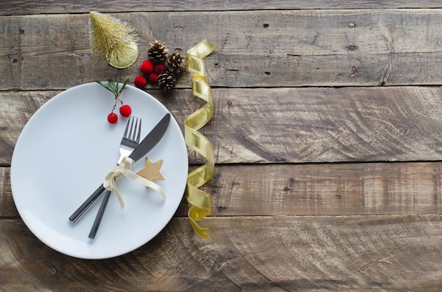 Plate with Christmas decoration on wooden background.