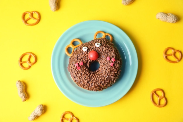 Plate with creative donut on color background