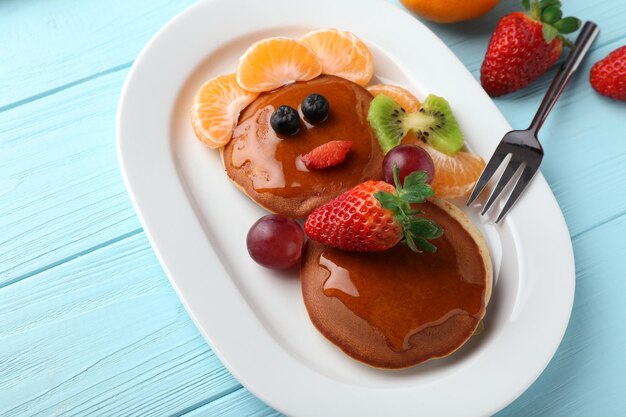 Plate with creative homemade pancakes on wooden table