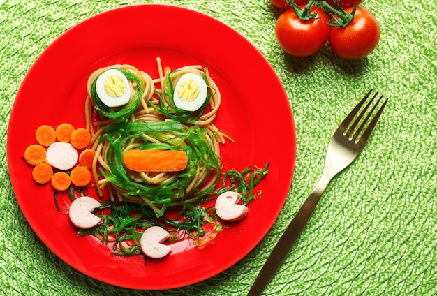 Plate with creative pasta for children on wicker mat