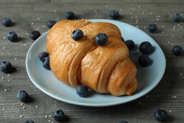 Plate with croissant and blueberry on gray textured table