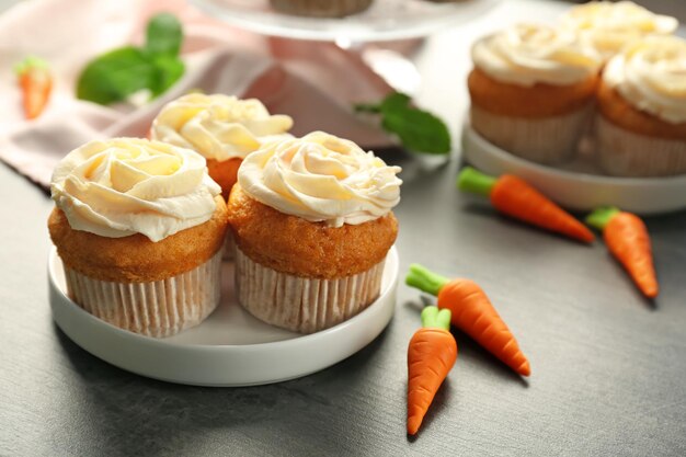 Plate with delicious carrot cupcakes on table